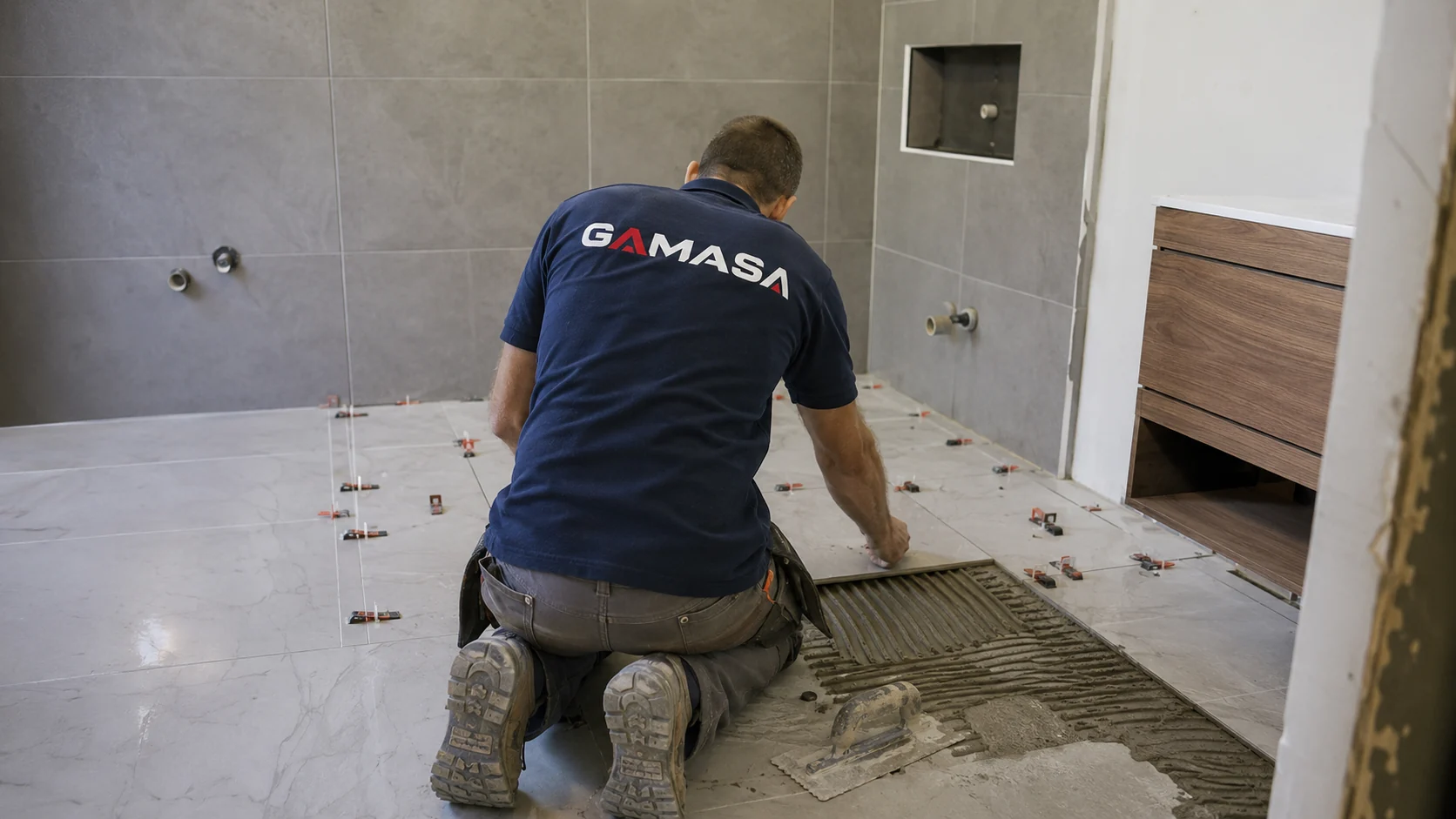 Profesional de GAMASA colocando pavimento cerámico en un baño