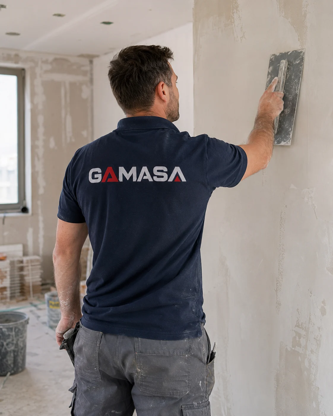 Trabajador de GAMASA preparando y alisando una pared en obra